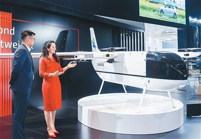 图为在第八届进博会上，亨睿碳纤维市场总监陈文瑾（右）向观众介绍中型电动垂直起降物流无人机 LEU100真机。受访者供图