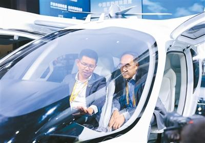 图为在第八届进博会上，黄雍威（左）在E20 eVTOL全尺寸真机内为观众作讲解。受访者供图