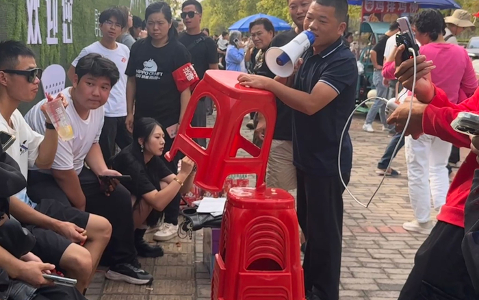 10月15日，凳子哥在鸡排摊前发凳子，维持现场秩序。  新京报记者 熊丽欣 摄