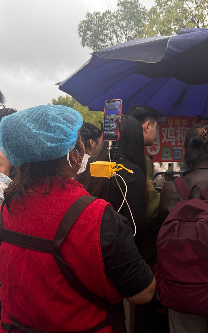 10月21日，隔壁卖手抓饼的大姐在直播鸡排哥。  新京报记者 熊丽欣 摄