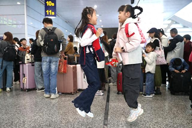 11月12日，浙江宁波，铁路宁波站迎来秋假出游高峰，两位小学生开心得“飞起”。视觉中国 图