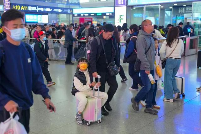 11月12日，成都东站，小朋友开心地坐在行李箱上“滑”行。成都商报 图