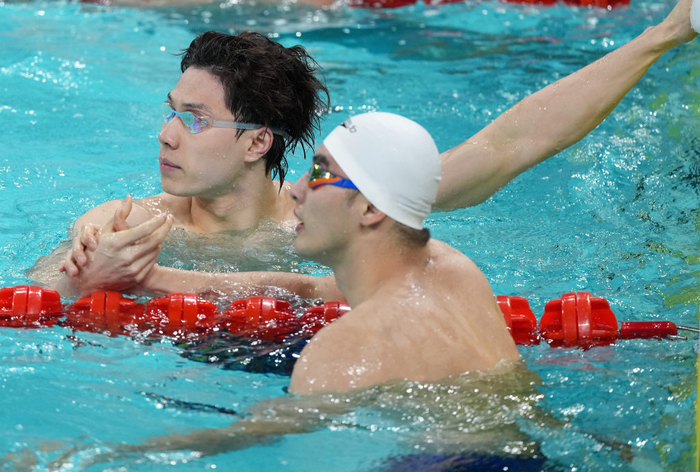 11月12日，上海队选手覃海洋（左）与队友郑英昊在男子50米蛙泳半决赛后握手致意。