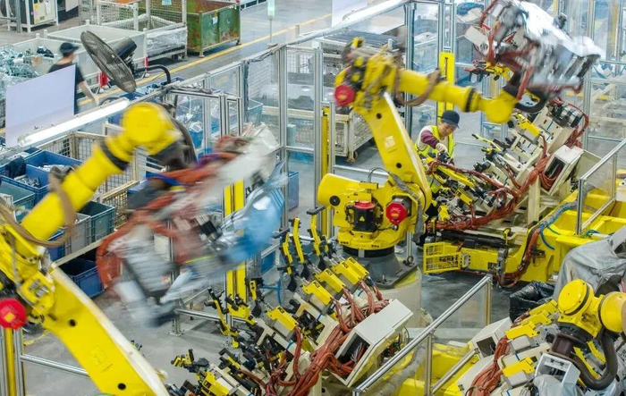 技术人员操控工业机器人生产新能源汽车配件。图源：新华社