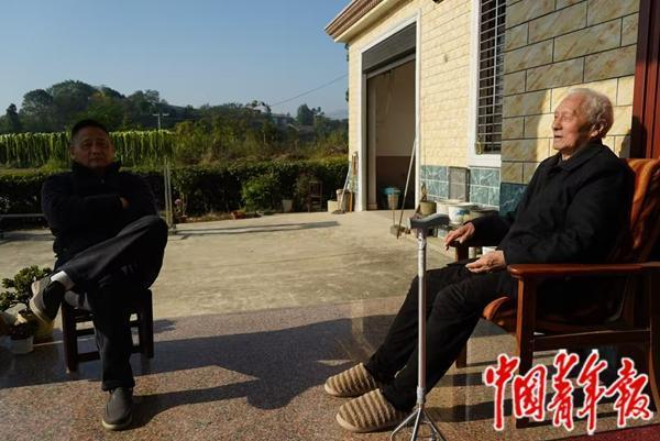 父子俩在屋外聊天，郑彩清喜欢晒太阳，郑军飞怕晒，坐在阴凉处。中青报·中青网记者 魏晞/摄