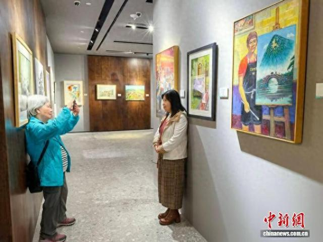 12月1日，“澳门美术协会会员作品展2025”在澳门巴黎人开幕。图为澳门市民在展出的画作前合影留念。中新网记者 郑嘉伟 摄