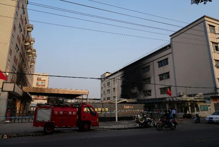 现场被警戒线围起，两侧建筑被烟火熏黑。