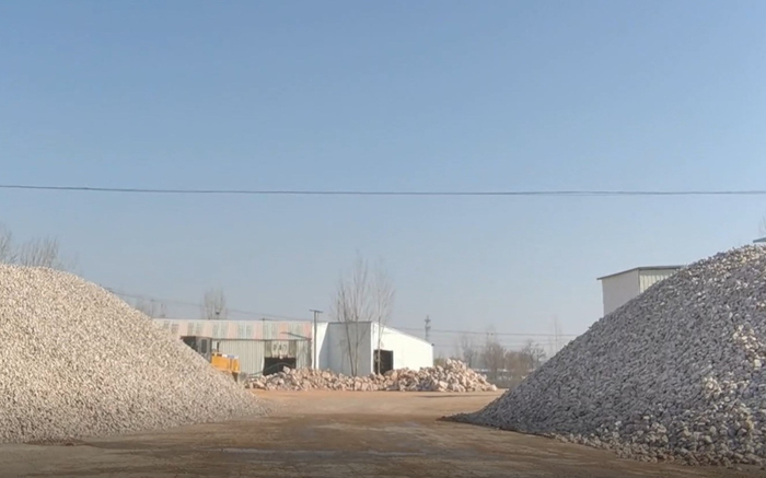 ▲11月29日，平邑县金星石材公司院内存放着圣泉生态公司卖来的原矿石（远处）和加工后的石子。新京报记者 李英强 摄