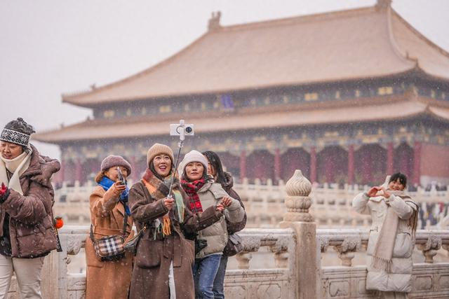 故宫雪花纷飞，红墙白雪相映成趣，吸引众多游客打卡拍照。北京日报记者武亦彬摄