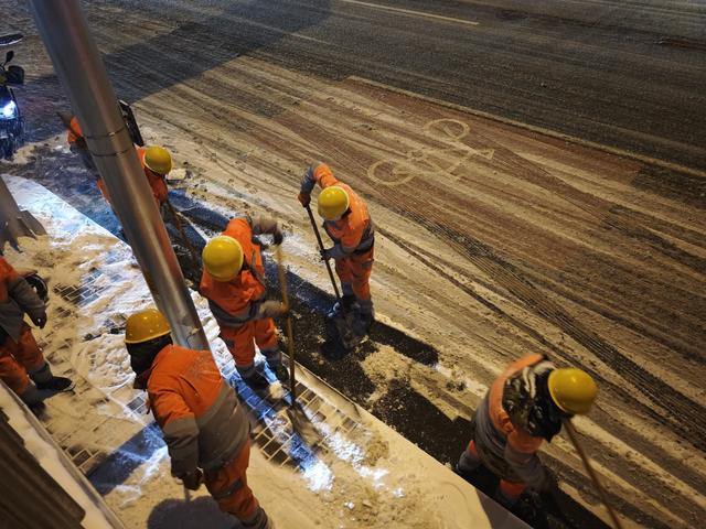 12月12日傍晚，环卫工人冒雪清理便道上的积雪，方便市民出行。北京日报记者吴镝摄
