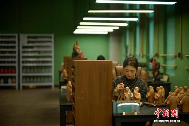 12月1日，在天津市泥人张世家绘塑老作坊3楼彩绘部，一名工艺美术师对泥塑坯体进行彩绘。中新社记者 佟郁 摄