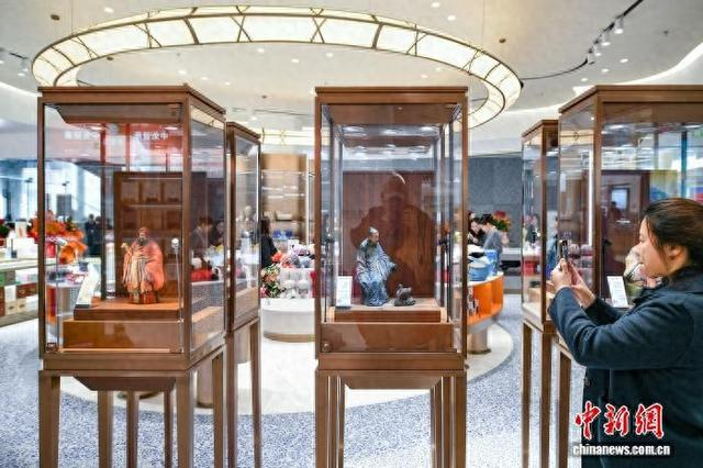 11月28日，天津首家市内免税店，顾客在“泥人张”彩塑展示柜前打卡拍照。中新社记者 佟郁 摄