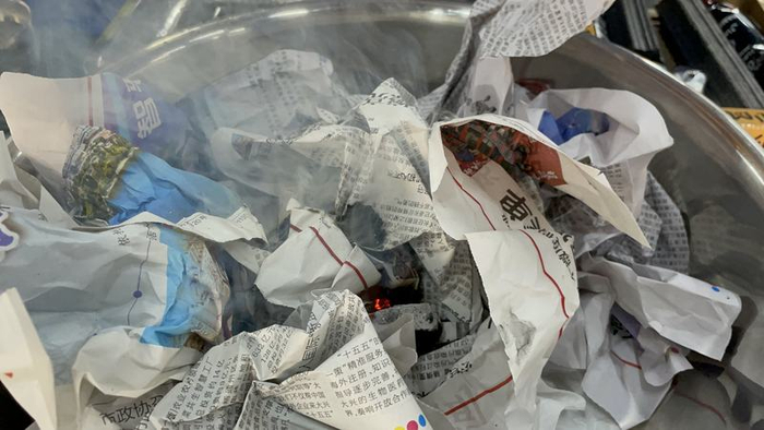 丢到纸堆里的已经“熄火”的木炭不一会儿就把纸引燃。新京报记者 张静姝 摄