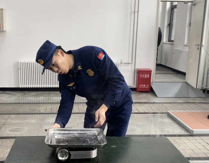 李炫展示错误用法，锅具过大，覆盖了卡式炉气罐。新京报记者 张静姝 摄