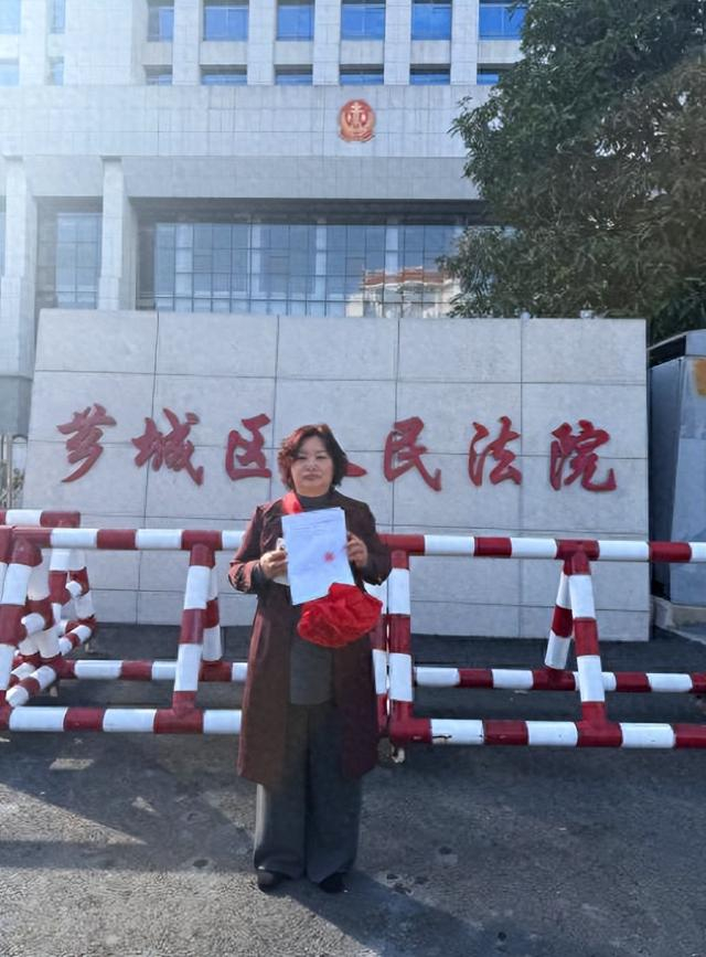 芗城区法院门口，林惠荣手持无罪判决书。图/王殿学