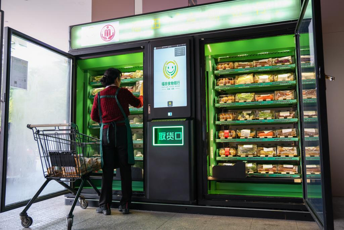 12月19日早上，在深圳市福田区益田村，工作人员正在将分装好的蔬菜放入“食物银行”智能柜机。新华社记者 梁旭 摄
