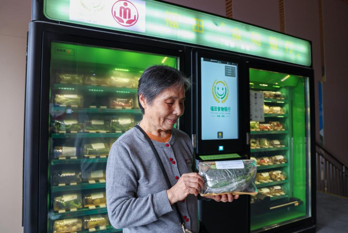 12月19日，74岁的刘云南在深圳市福田区益田村的“食物银行”扫码领取到一包蔬菜。新华社记者 梁旭 摄