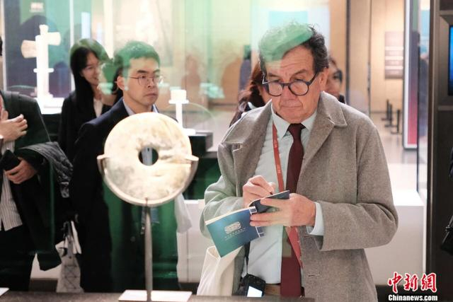 2024年11月25日，浙江杭州良渚博物院，外籍考古学家站在良渚玉璧前仔细做记录。 中新社记者 曹丹 摄