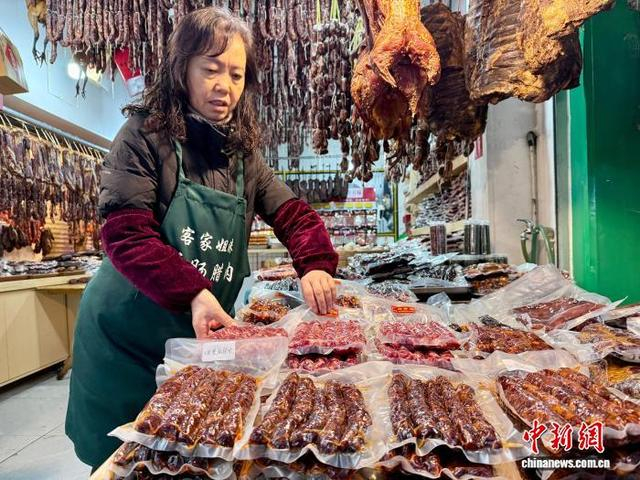 图为新开寺街一店家在摊位旁整理香肠。何美锟 摄