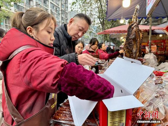 图为新开寺街一店员在为顾客包装腊味食品。何美锟 摄