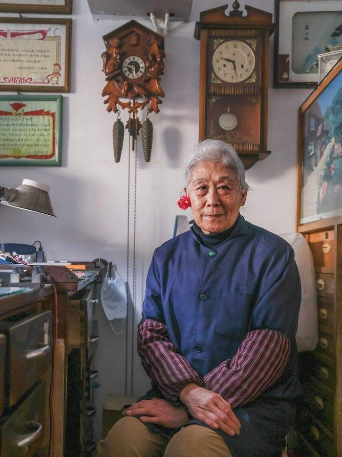 刘宪平身穿蓝布工作服，头发已经花白，修表的装扮多年未变。