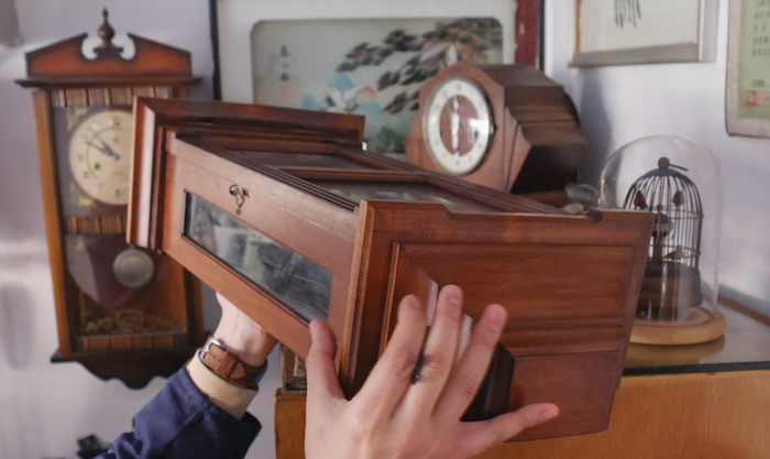 袁亮在放置客人送来的老钟，店里还有许多老钟表。