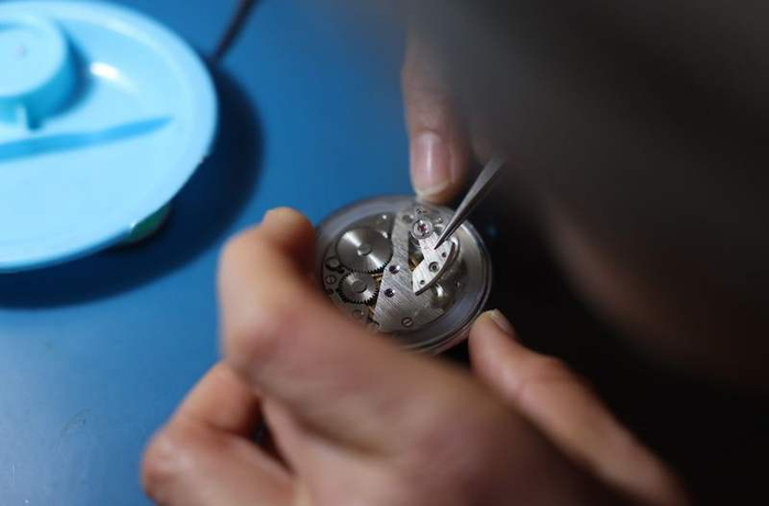 刘宪平用镊子夹起一块吉林金鹿怀表中的零件。