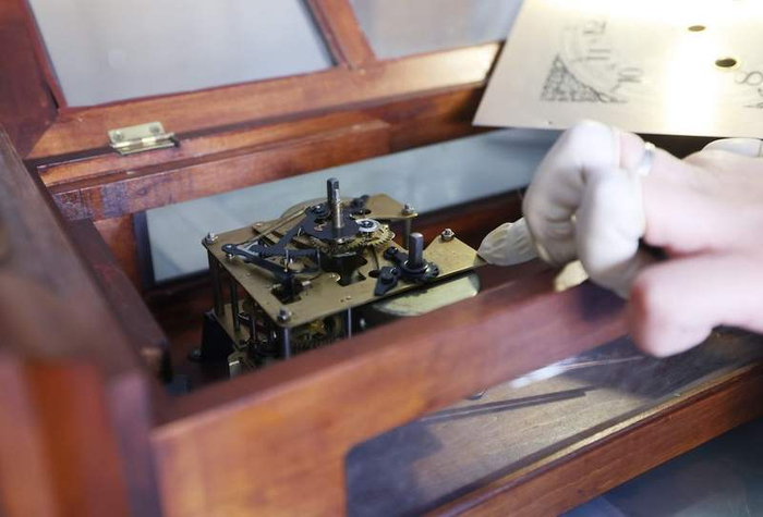 袁亮拆开老钟的盖板查找问题。