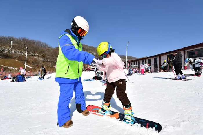在湖北省襄阳市保康县横冲国际滑雪场，滑雪教练在指导小朋友练习滑雪。杨韬 摄