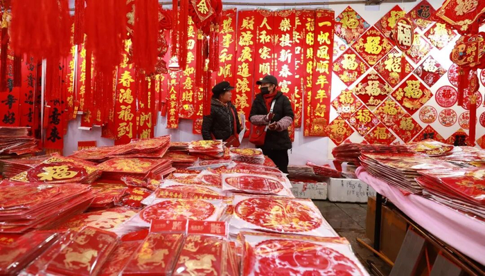 1月20日，市民在贵州省都匀市文峰广场年画市场选购春节饰品。新华社发（肖伟摄）