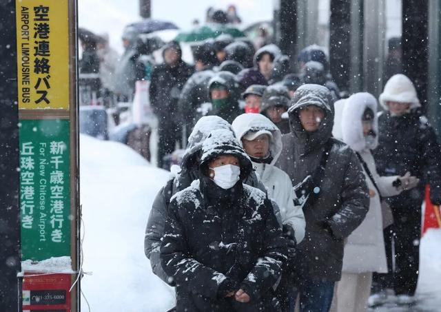 当地时间2026年1月26日，日本北海道札幌市，人们在暴雪中等待车辆。视觉中国 图