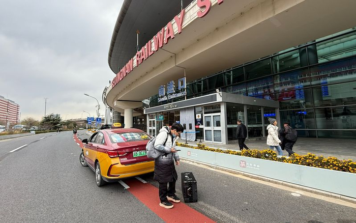 北京南站路南广场路段，一名旅客在新开放的落客区下车，身后就是进站口。资料图片/新京报记者 王贵彬 摄