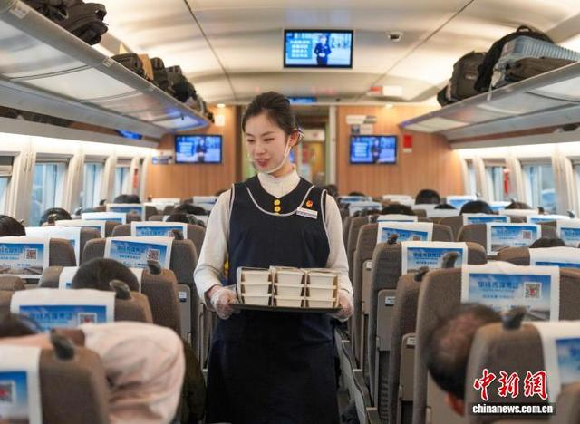 工作人员端着餐食行走在列车车厢内。华铁旅服公司供图