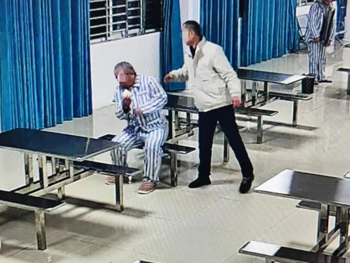 ▲12月17日早晨，襄阳宏安精神病医院的一名护工正在扇一名病人耳光。视频截图