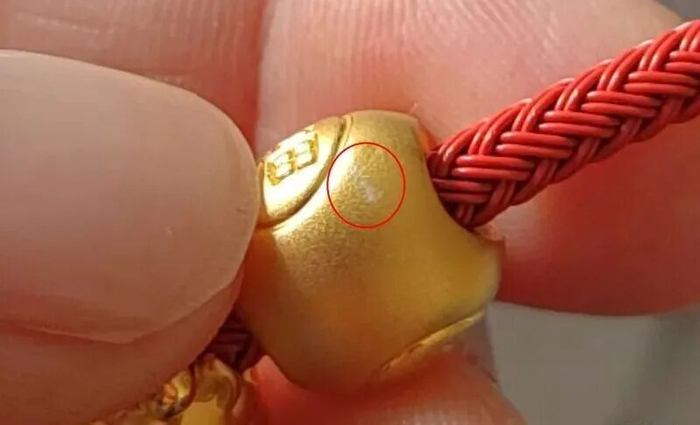 照片显示，挂坠刮花位置出现白色痕迹。