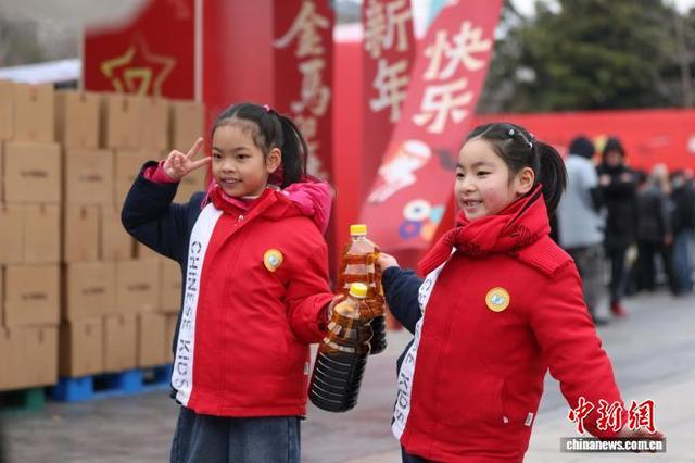 2月7日，江苏镇江，老字号企业设立的酱油供应点广场上，小朋友拿着装满酱油的容器拍摄照片。中新社记者 泱波 摄