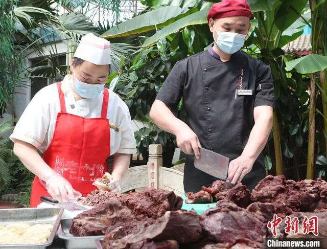 图为河北省保定市徐水区漕河全驴宴大酒店的两位师傅正在切驴肉、夹火烧。 中新社发 雷永怀 摄