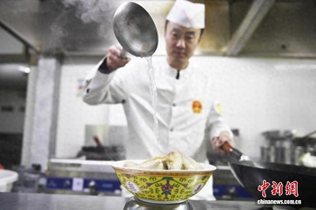 2月5日，吉林石光酒楼的后厨里，厨师烹饪“满族八大碗”菜品小鸡榛蘑粉。 中新社记者 石洪宇 摄