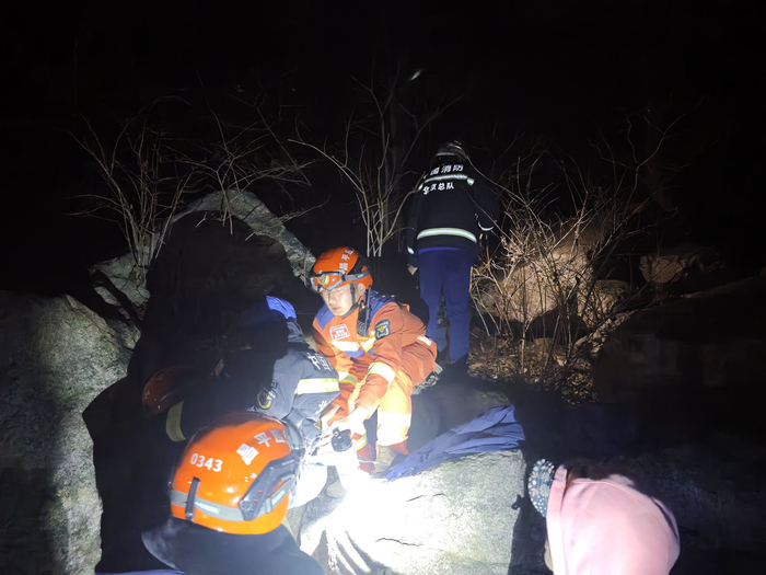 夜间进山救援，只能依靠头灯和手电进行照明。遇到乱石，消防员通过后，再协助被救人员通过。 受访者供图