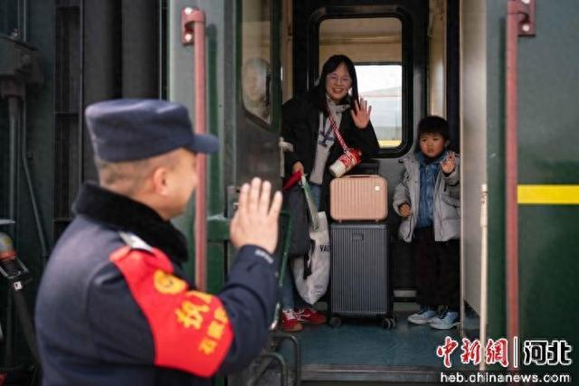 图为石家庄铁路公安处清河城站派出所民警邱传亚帮助带孩子的旅客乘车并于其挥手告别。 石家庄铁路公安处 供图