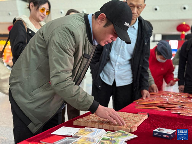 2月10日，在厦门站“话百家姓 过中国年”主题文化活动现场，台胞谢睿峰在寻找自己姓氏的印章。新华社记者 付敏 摄