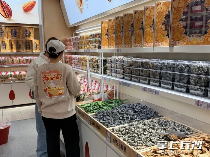 薛记炒货门店内，店员正在向顾客介绍产品。