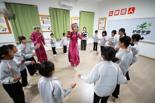 全国政协委员、乐作舞非遗传承人杨钰尼（中）教孩子们跳乐作舞。董腾飞/摄