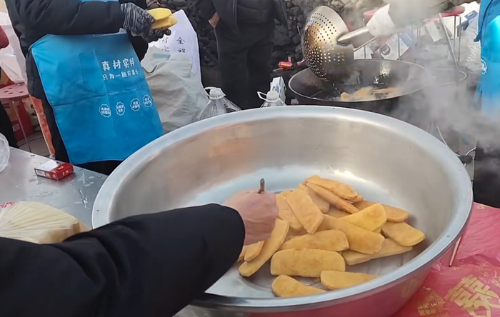 陕北农村红事乡宴上的炸油糕，这边出锅儿捞出来，那边就趁热吃上了。