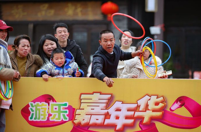 　　↑1月25日，游客在贵州省黔东南苗族侗族自治州丹寨县万达小镇庙会上玩套圈游戏。新华社发（黄晓海 摄）