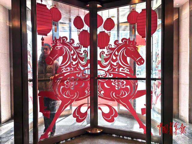 2月15日，北京东四环外某饭店，转门玻璃上贴着生肖马年的剪纸图案。中青报·中青网记者 陈剑/摄