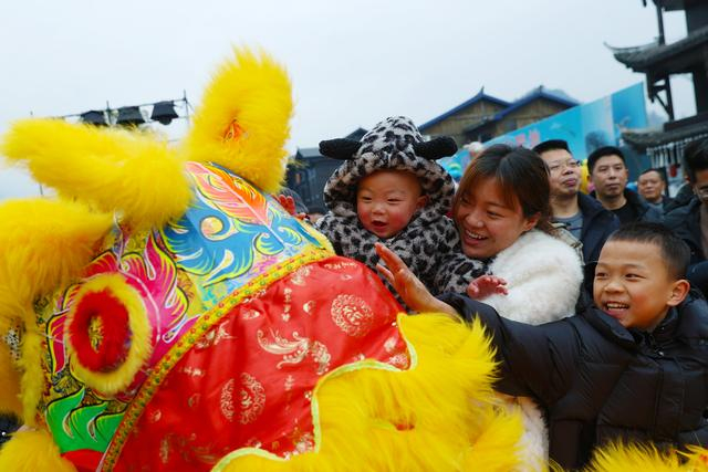 2月17日，游客在重庆市黔江区濯水古镇参加摸狮头活动。新华社发（杨敏摄）