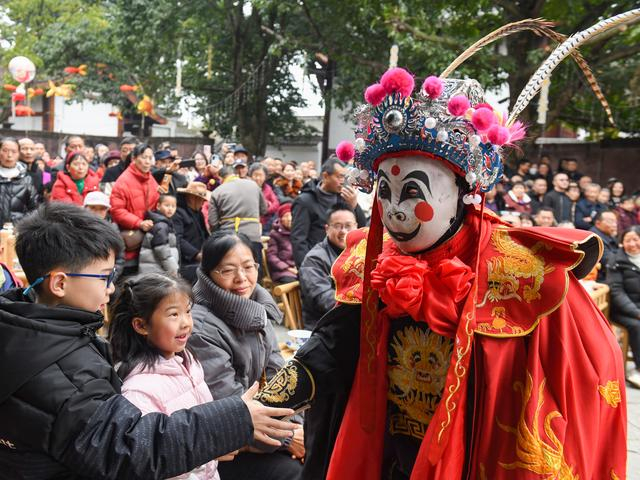 2月17日，在四川省阆中市阆中古城，表演川剧变脸的演员与观众互动。新华社发（王玉贵摄）