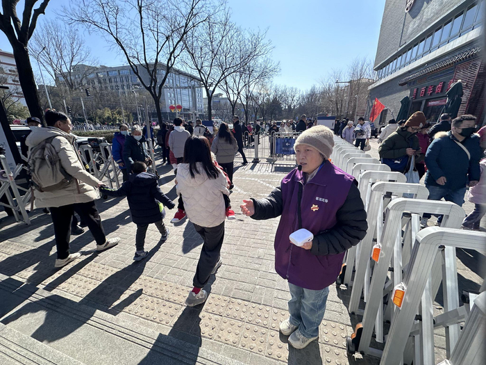 在地面出站口，客流疏导员许会侠提醒游客注意安全。新京报记者 裴剑飞 摄