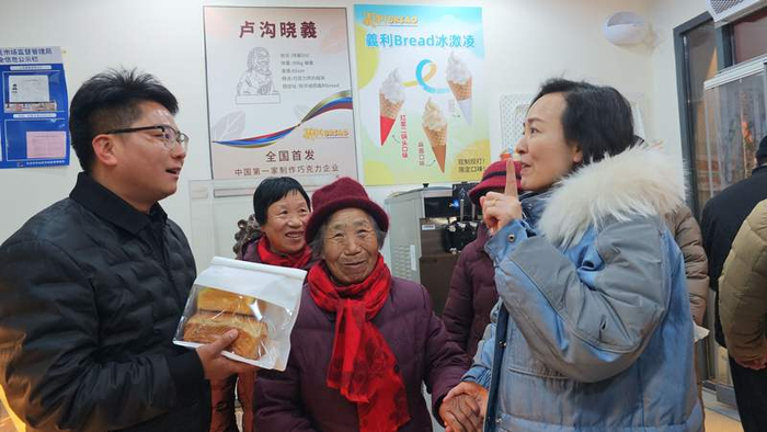 丰台区文旅局局长吴婧给一家人推荐总书记买过的同款面包。新京报记者 王巍 摄